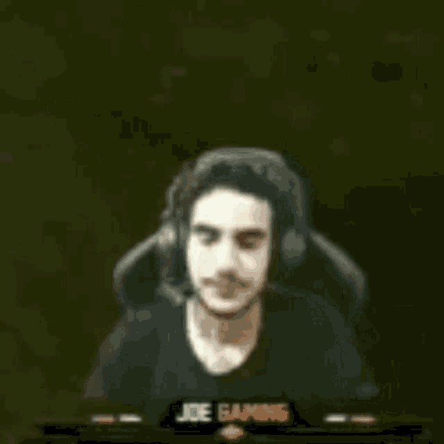 a man wearing headphones is sitting in front of a computer screen and holding his head .