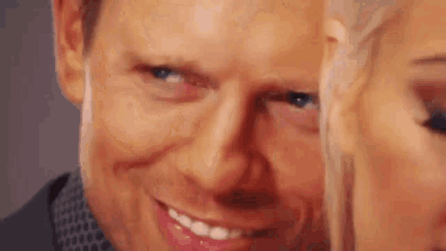 a close up of a man 's face with a woman 's face behind him .