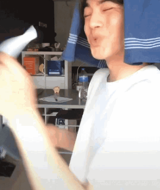 a person with a blue towel on their head blow drying their hair with a hair dryer