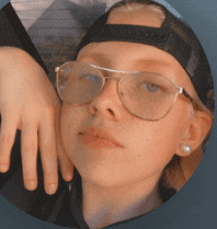 a young girl wearing glasses and a black hat looks at the camera