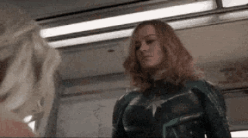 a woman in a superhero costume is standing next to another woman .