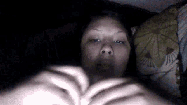 a woman laying in bed with a floral pillow