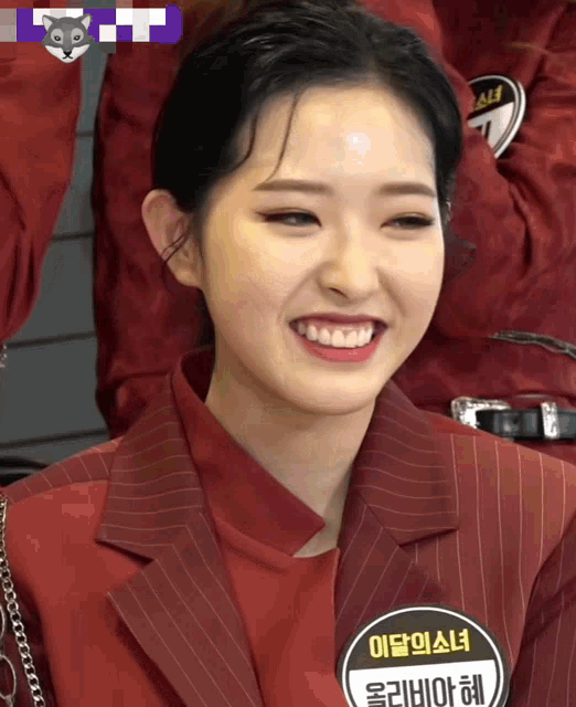 a woman in a red suit has a name tag with korean writing on it
