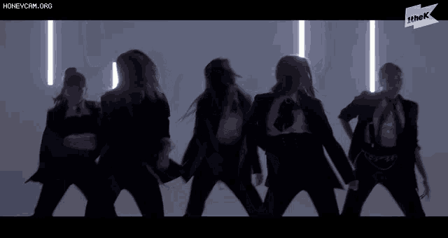 a group of women are dancing in front of a sign that says ' the k ' on it