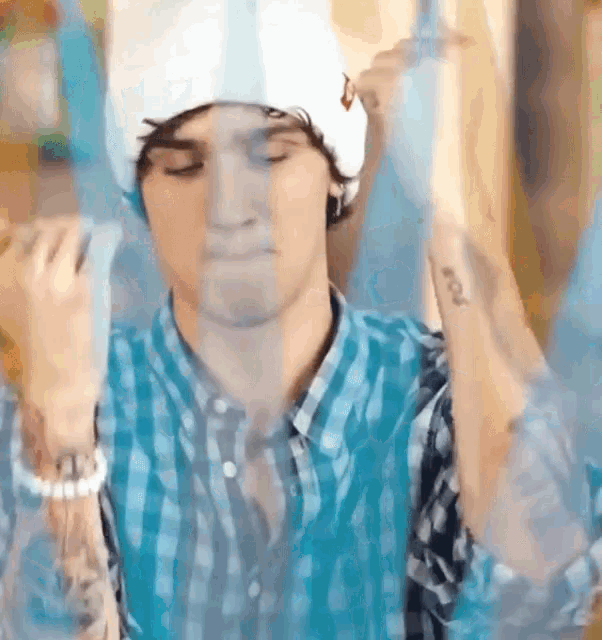 a man wearing a plaid shirt and a white hat has a tattoo on his wrist that says fox