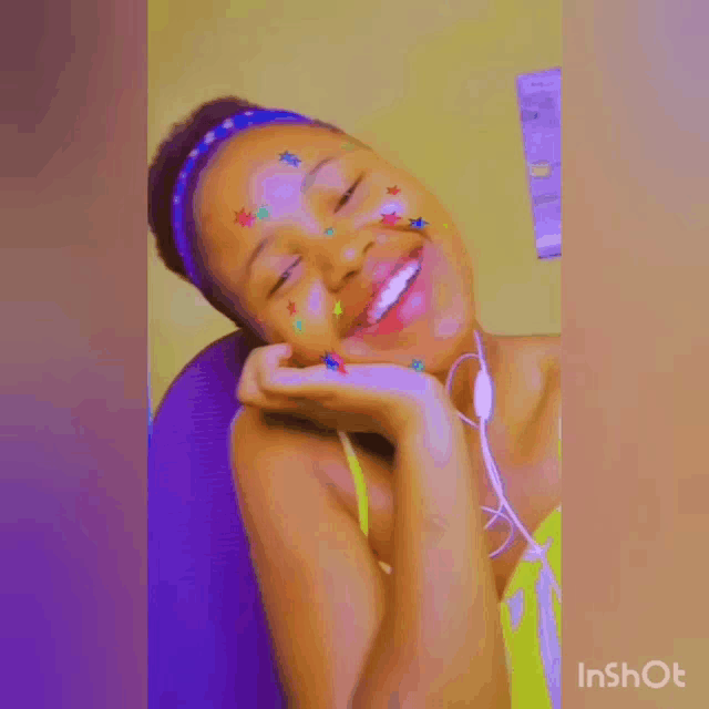 a girl with stars on her face is smiling and holding her hand to her face .