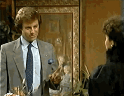 a man in a suit and tie is talking to a woman in a black coat .