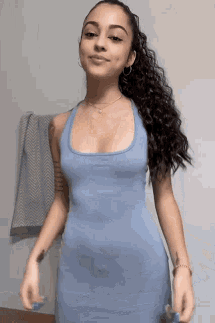 a woman in a blue dress is standing in front of a wall with a towel on it .