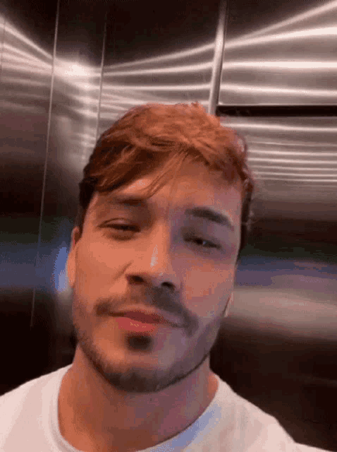 a man with a beard and red hair is standing in an elevator .
