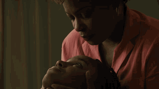 a woman in a pink shirt holds the head of another woman