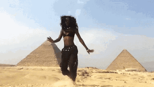 a woman is jumping in the air in front of pyramids in the desert