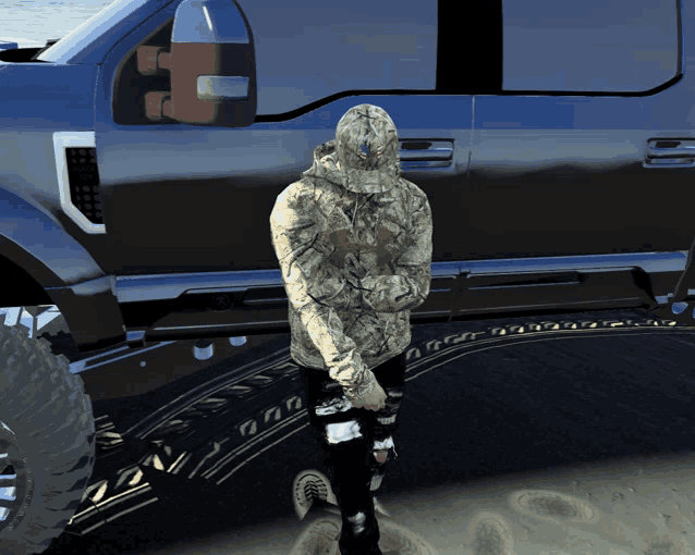 a man wearing a camo under armour hoodie stands in front of a blue truck