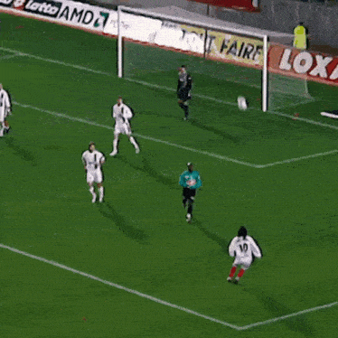 a soccer player with the number 10 on his shorts is dribbling the ball