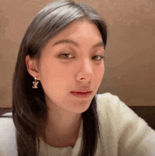 a close up of a woman wearing earrings and a white shirt .