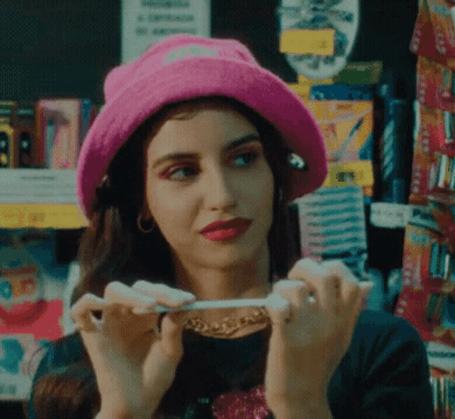 a woman wearing a pink hat is holding a cigarette in her hand .