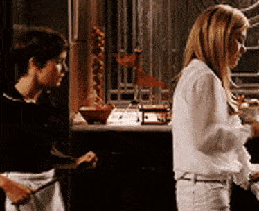 a woman in a white shirt is standing next to another woman in a black shirt