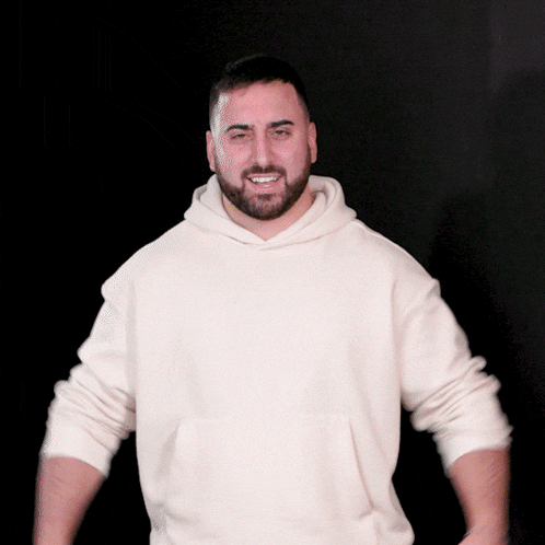 a man with a beard is wearing a white hoodie and smiling