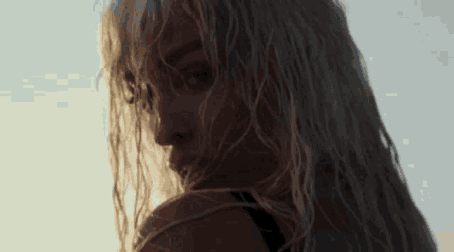 a close up of a woman 's face with long blonde hair looking over her shoulder .