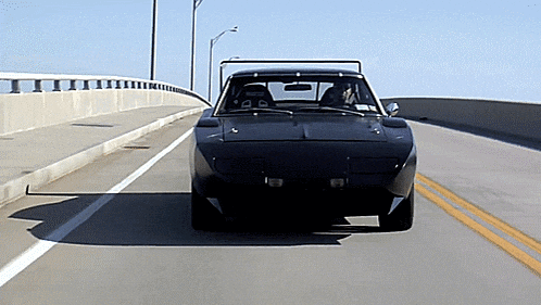 a black car is driving down a highway with a yellow line in the middle