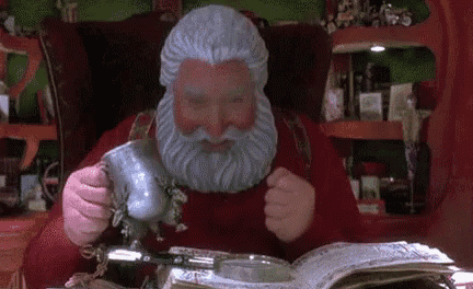 a statue of santa claus is looking through a magnifying glass at something in a book .