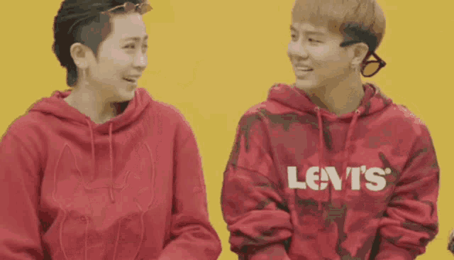 a man wearing a red levi 's hoodie laughs with another man