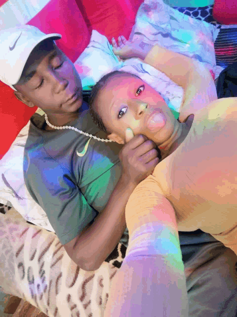 a man wearing a nike hat holds a woman 's face