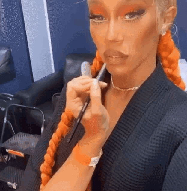 a woman is applying makeup with a brush to her face .