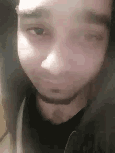 a close up of a man 's face with a beard and a black shirt