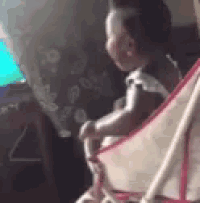 a baby is sitting in a stroller in front of a computer screen .