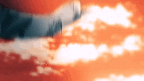 a blurry picture of a sunset with clouds and trees in the background