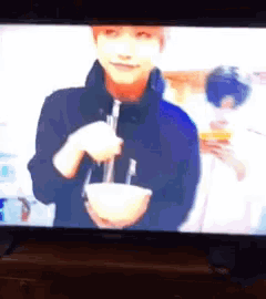 a tv screen shows a man holding a bowl with a straw