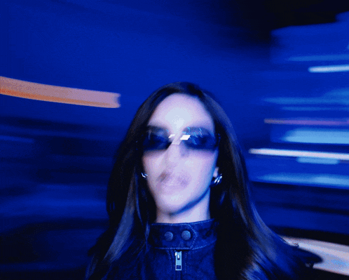 a blurry photo of a woman wearing sunglasses and a jacket