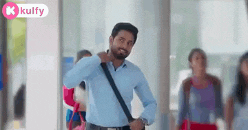 a man with a beard is walking down a hallway carrying a shoulder bag .