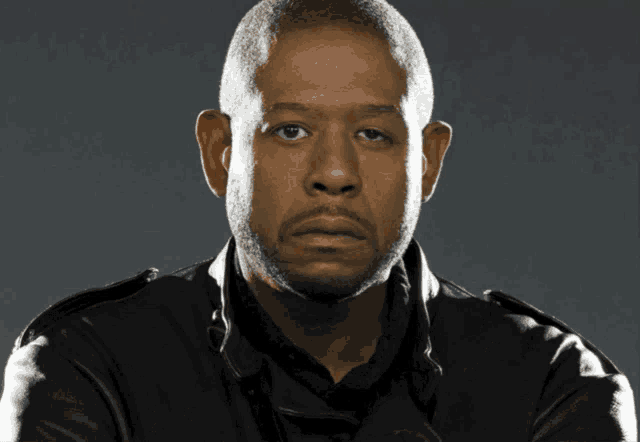 a man in a black jacket looks at the camera