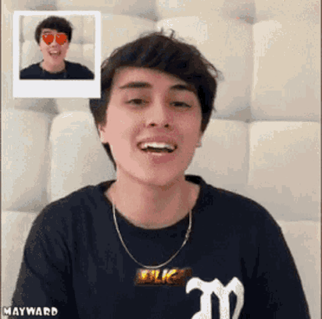 a young man wearing a black shirt with the letter m on it is smiling