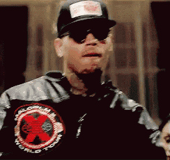 a man wearing a hat and sunglasses has a patch on his jacket that says world
