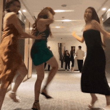 a group of women are dancing in a hallway with a man standing behind them