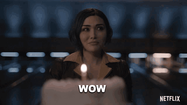 a woman stands in front of a cake with a lit candle and says wow