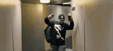 a man is walking down a hallway with a backpack and a cell phone .
