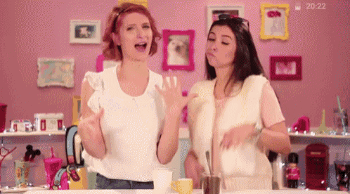 two women standing next to each other in front of a pink wall with the time 20:22 on the bottom