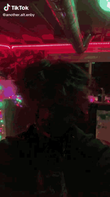 a person in a clown costume is standing in front of a neon sign .