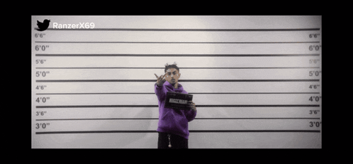 a man in a purple sweatshirt is standing in front of a police lineup