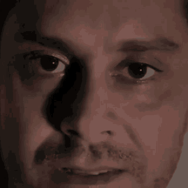 a close up of a man 's face with a shadow on his eye