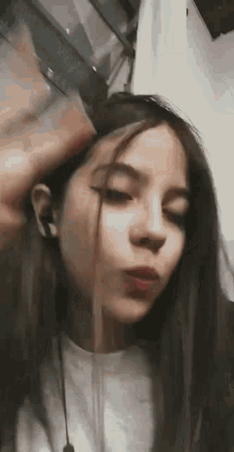 a close up of a girl 's face with a person putting their hand on her head .