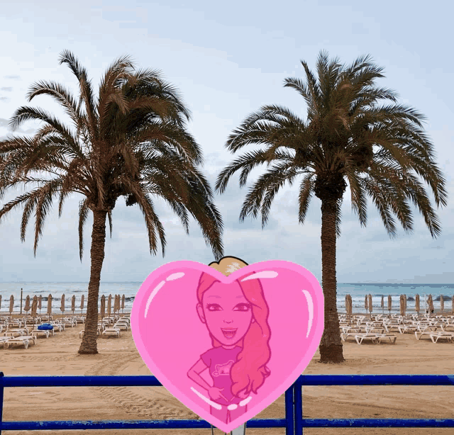 a pink heart with a cartoon girl on it in front of a beach