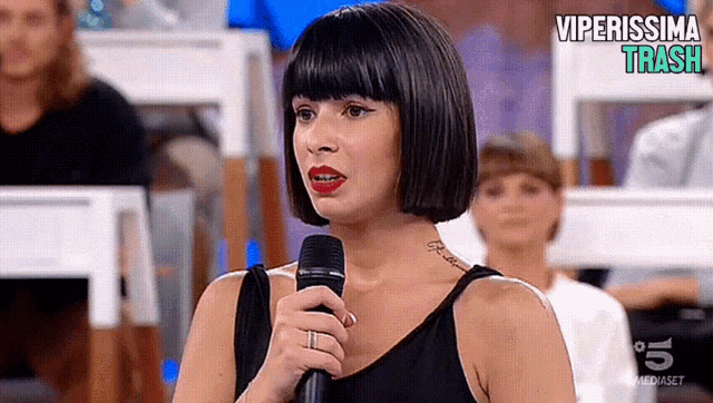 a woman holds a microphone in front of a screen that says viperissima traccia
