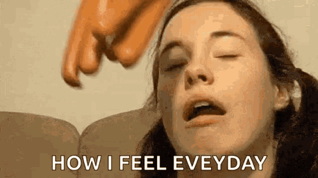 a woman is sitting on a couch with her eyes closed and a hand on her face .