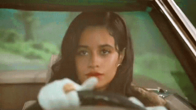 a woman is driving a car while holding a stuffed animal in her hand .