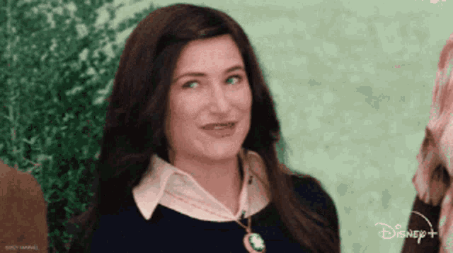 a woman is wearing a necklace with a disney logo in the background