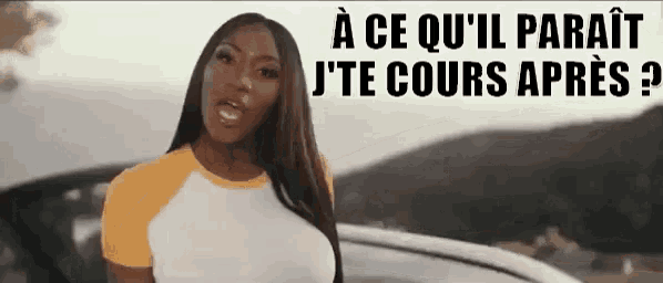 a woman is standing in front of a car and talking in french